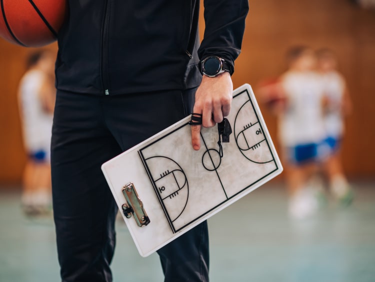 man holding a playbook on a basketball court