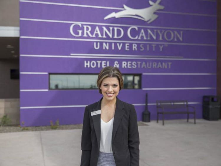 young woman in a blazer standing in front of the GCU hotel front desk