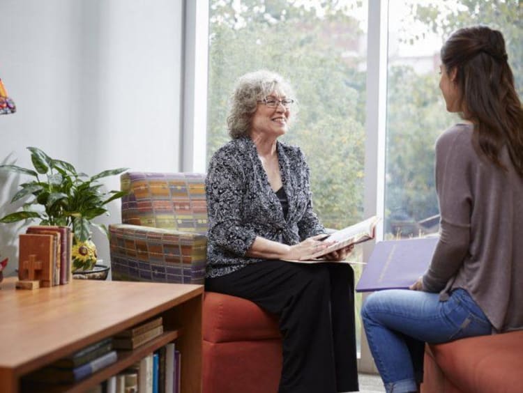 A life coach smiles while meeting with a younger female