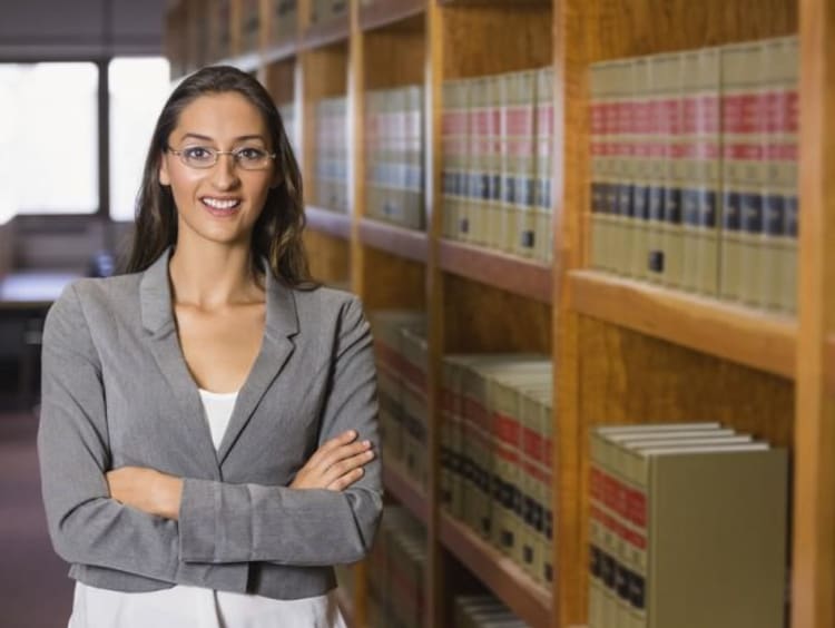 woman posing by a bookshelf