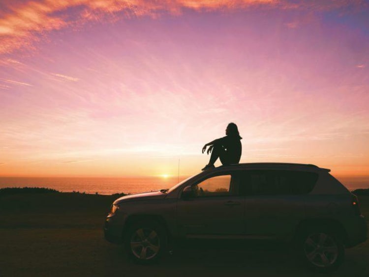 person sitting on his car outside