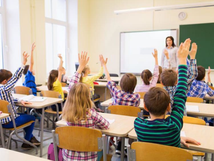 bright classroom full of students raising hands