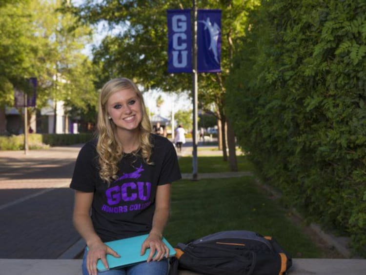 Blonde GCU Honors College student sits outside