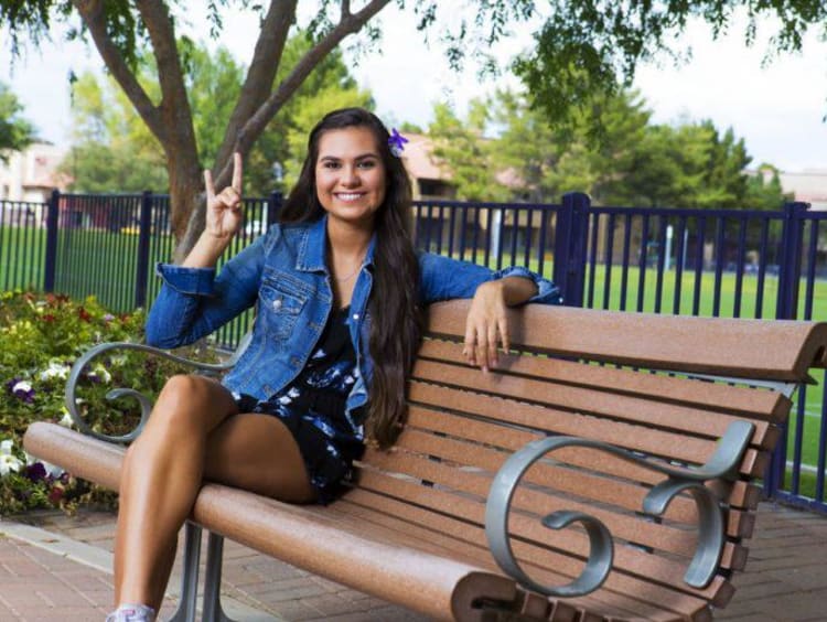 Tatum sitting on a bench on campus