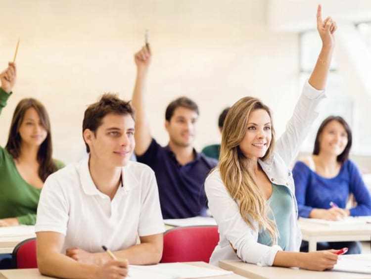 kids in classroom raising their hands