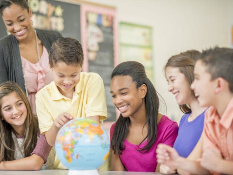 close up of students smiling around a globe