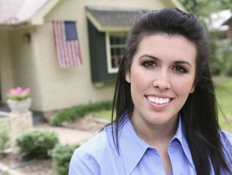 Beautiful woman in front of a house with an American flag floating