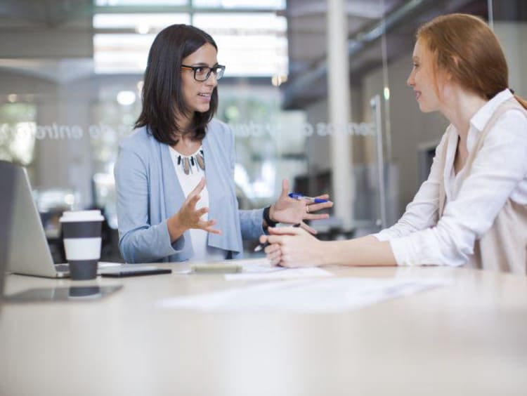 Life coach sits with a client in conference room with glass walls