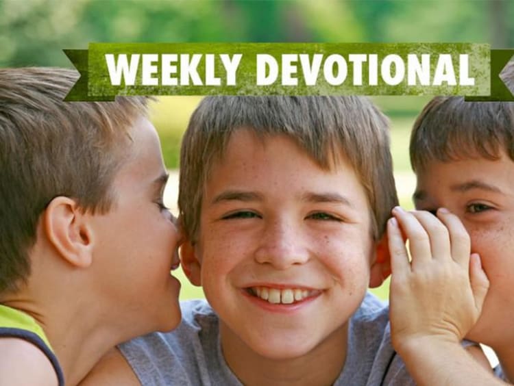 Students whispering to each other under the weekly devotional banner