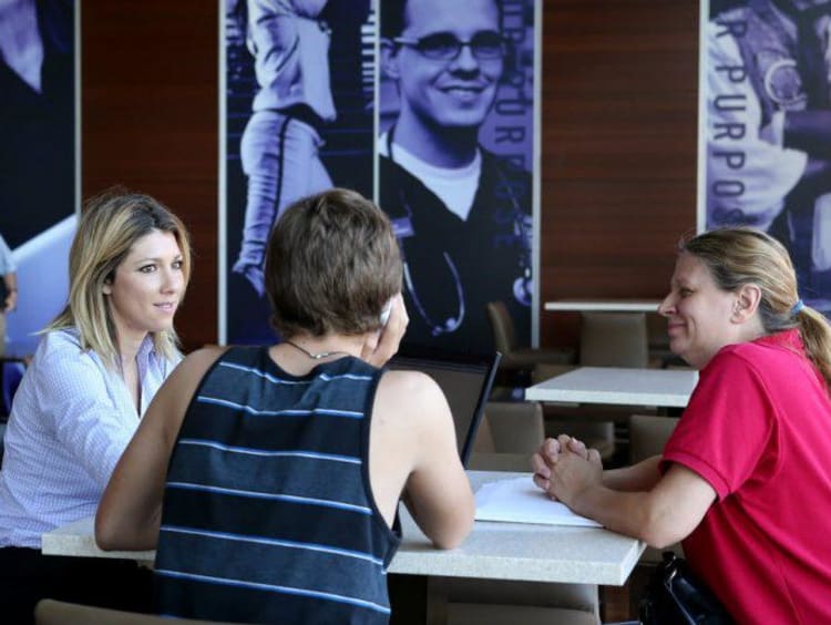 three people sitting around a table and talking