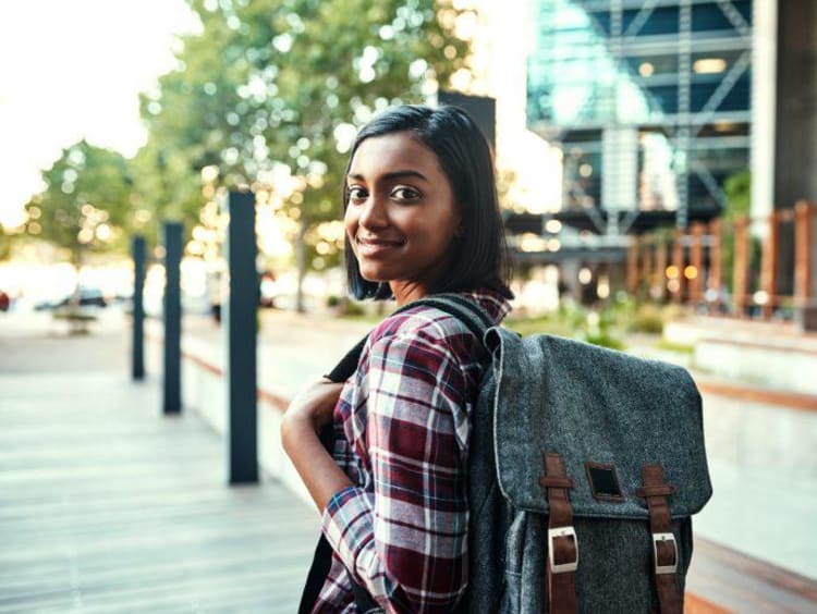 woman holding a backpack looking back at the camera