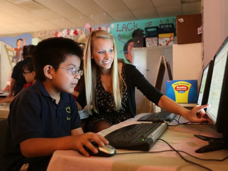 Teacher helping young boy with the computer