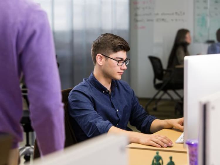a guy with glasses typing on the computer