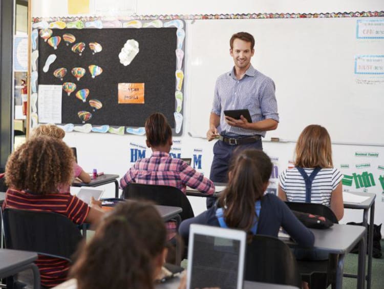 Male instructor holds tablet facing students