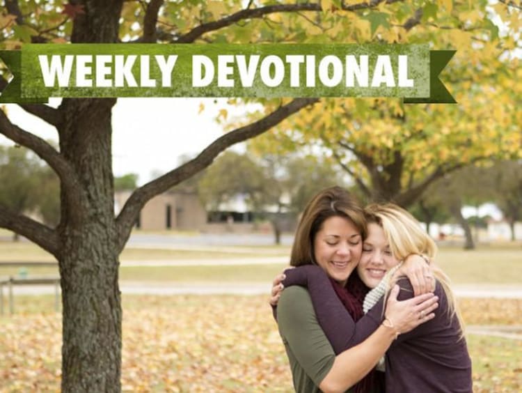 Two girls hugging under the Weekly Devotional banner