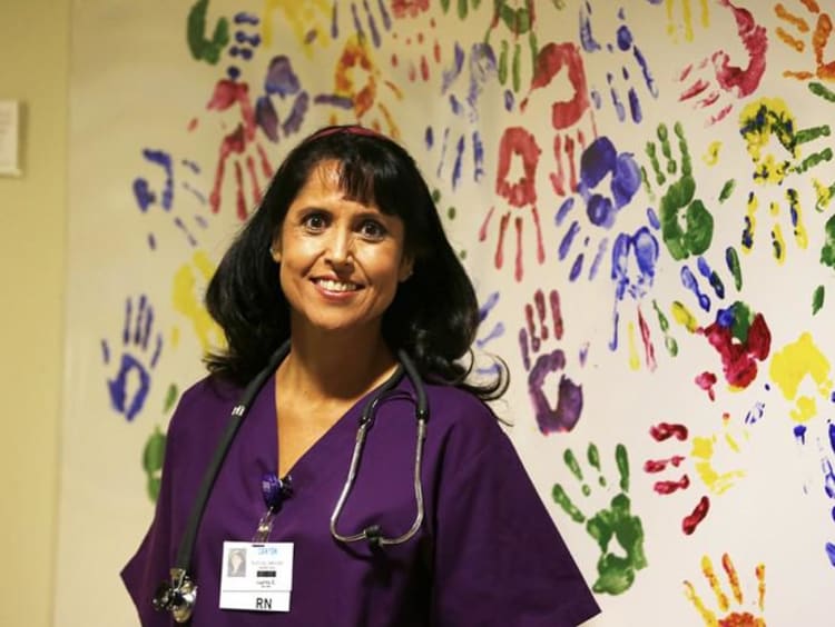 Nurse next to wall full of colorful handprints
