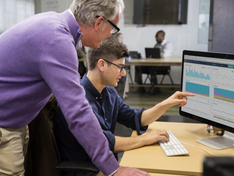 student showing professor something on a computer