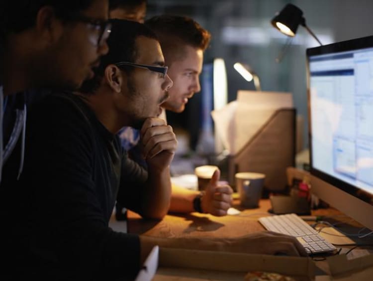 three men looking at a computer