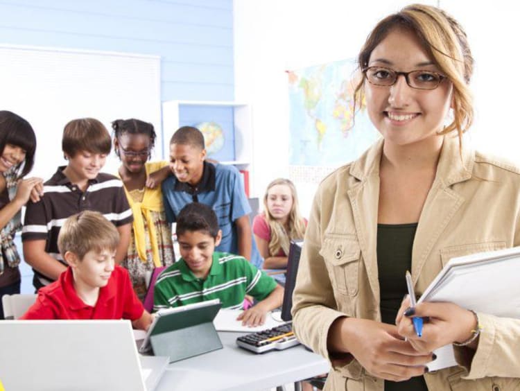 teacher smiling and students working in the background