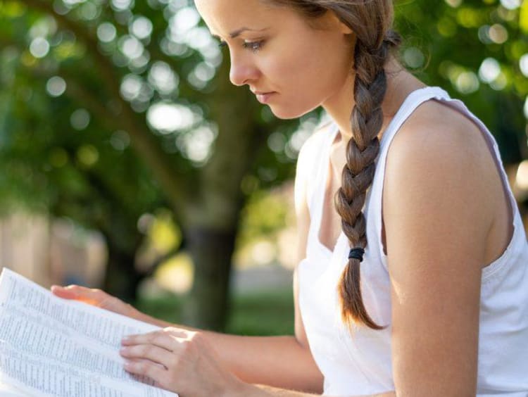 woman reading her bible outside