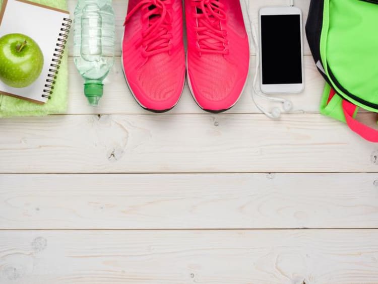 Sports gym bag contents lined up with bright pink athletic shoes in middle