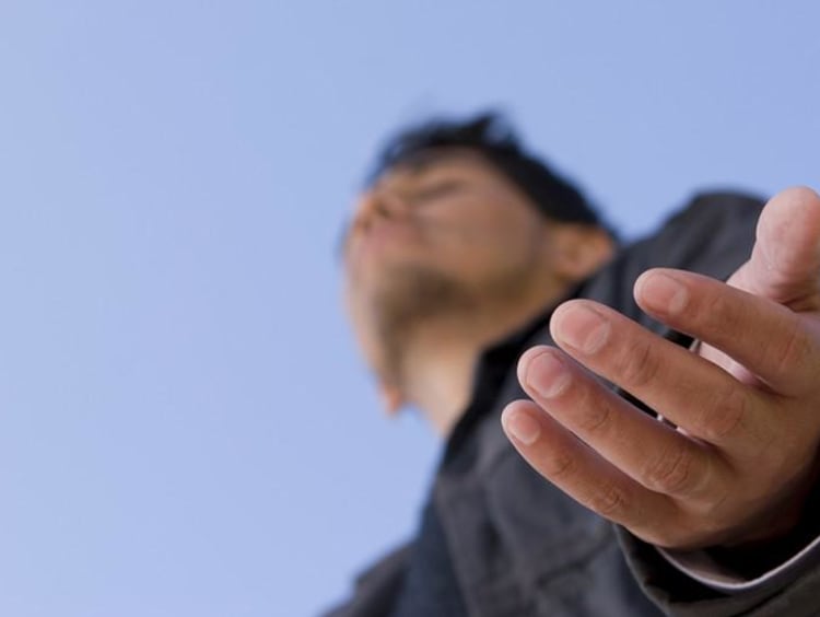 Man holds his hands out with eyes closed to receive God's Blessing