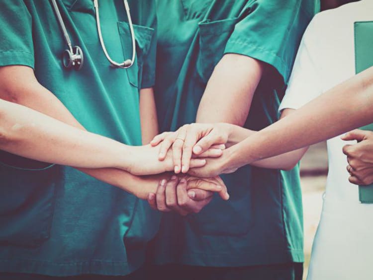 a group of nurses putting their hands together for a cheer