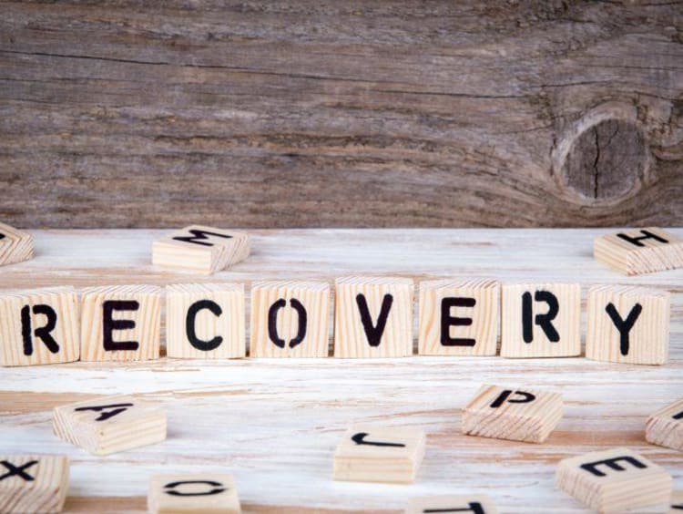 Letters on upright wood squares spell out recovery