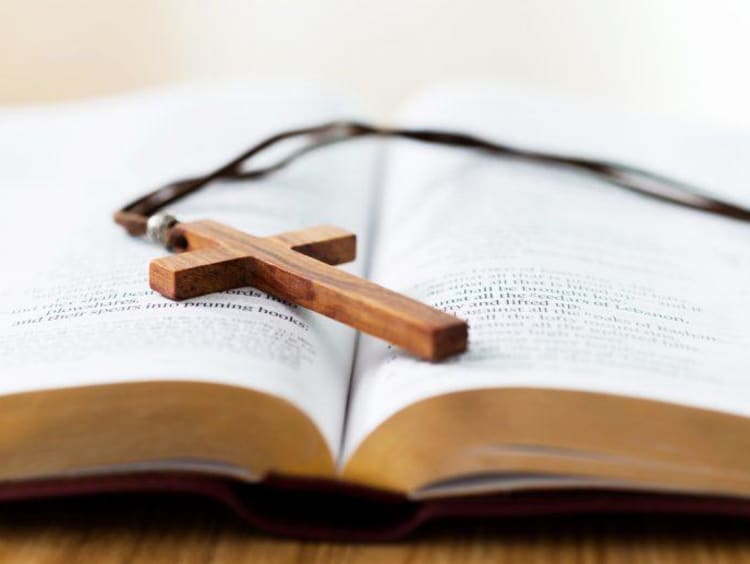 bible with a cross necklace sitting on top