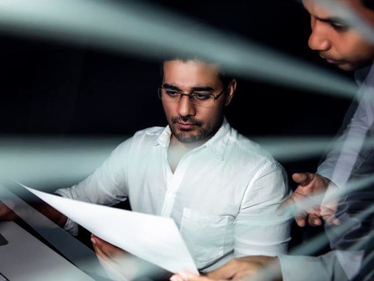 man showing another man a piece of paper