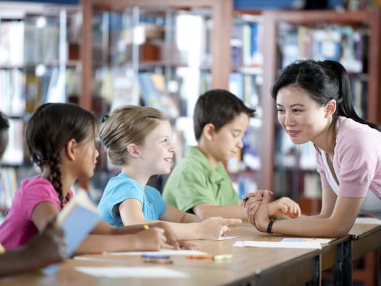 Woman teacher speaking to group of young students