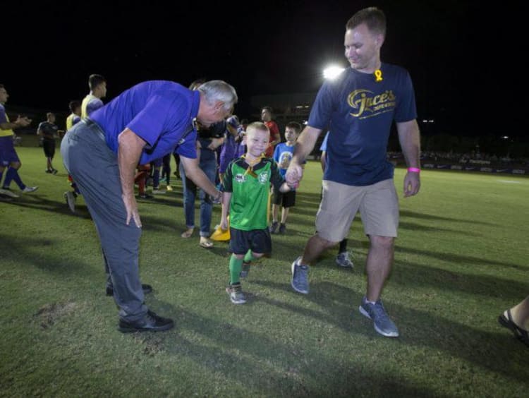 GCU's soccer team playing ball with a 10-year-old boy