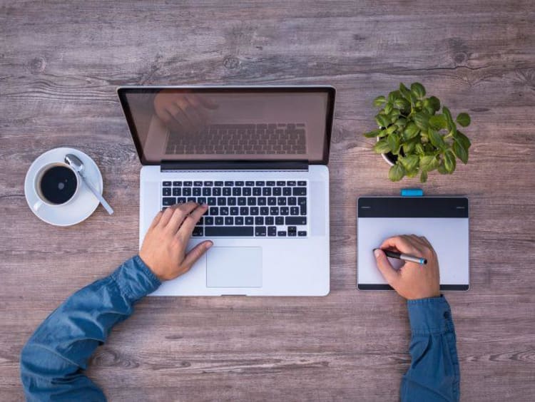 typing on computer with coffee