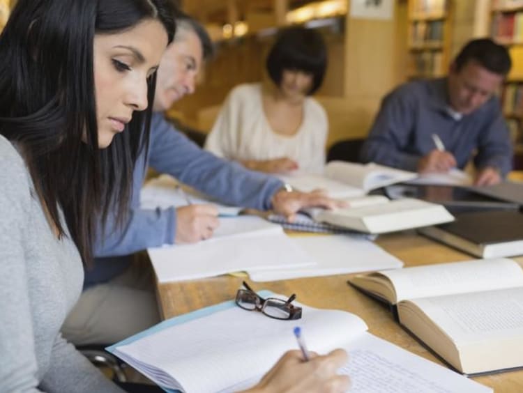 Group of adult students do course work in a library