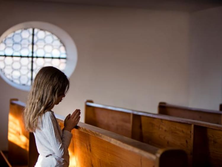 Little girl praying on pew