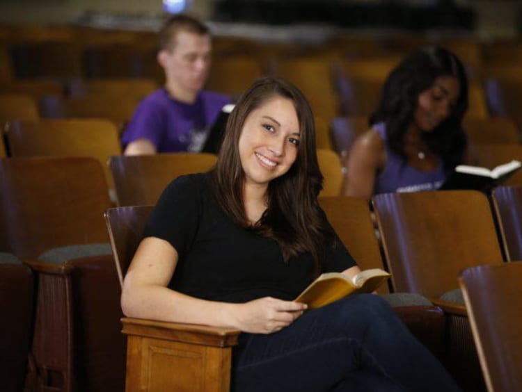 A student sitting in an auditorium reading