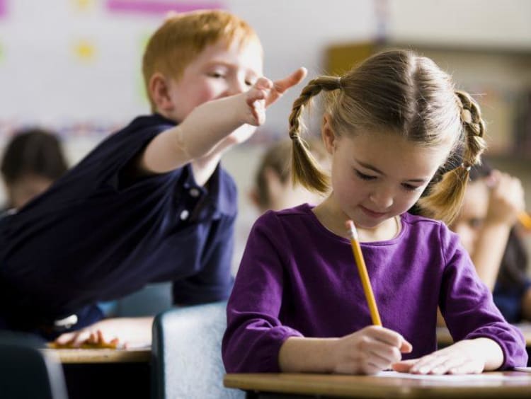 Little boy about to pull little girl's braid in class