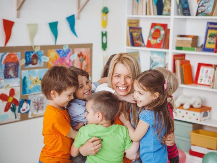 little students hugging female teacher