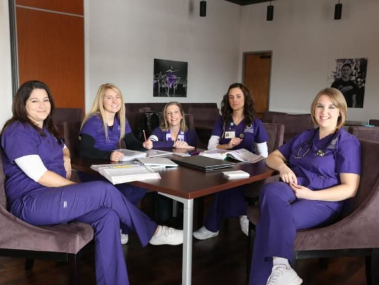 five nurses sitting around a table working