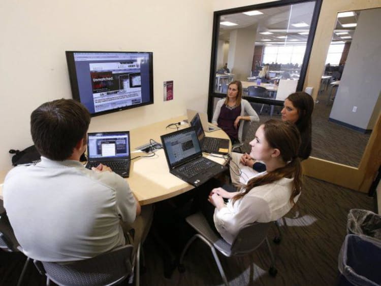 Group of people gathered around with laptops