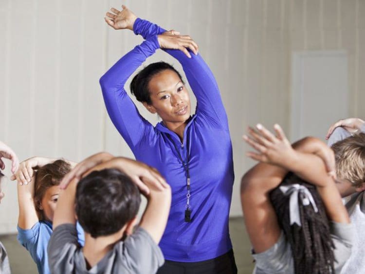 PE teacher stretches with students