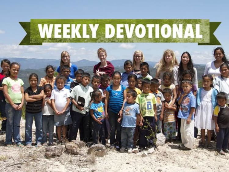 Group of global outreach volunteers standing behind students