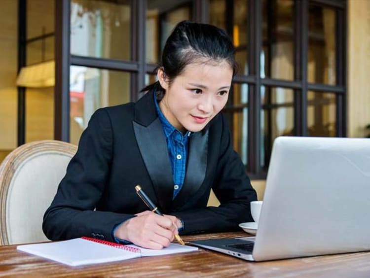 girl writing and looking at a computer