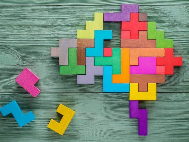 Colored puzzle pieces form a brain shape with a few missing pieces