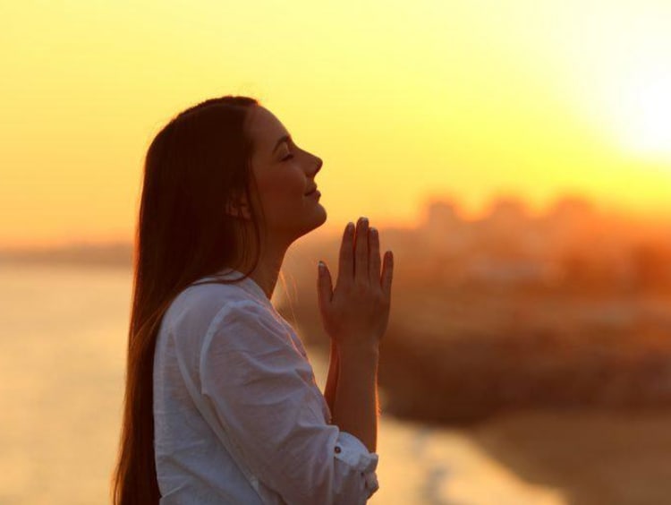 woman praying during sunrise or sunset