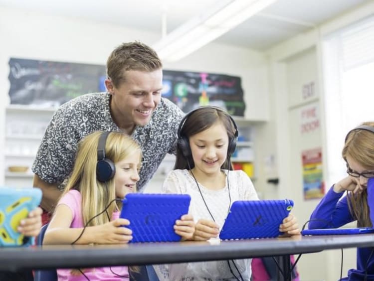 Teacher helping students with laptops