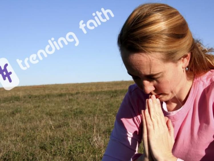 A woman praying in a field under the Trending Faith logo