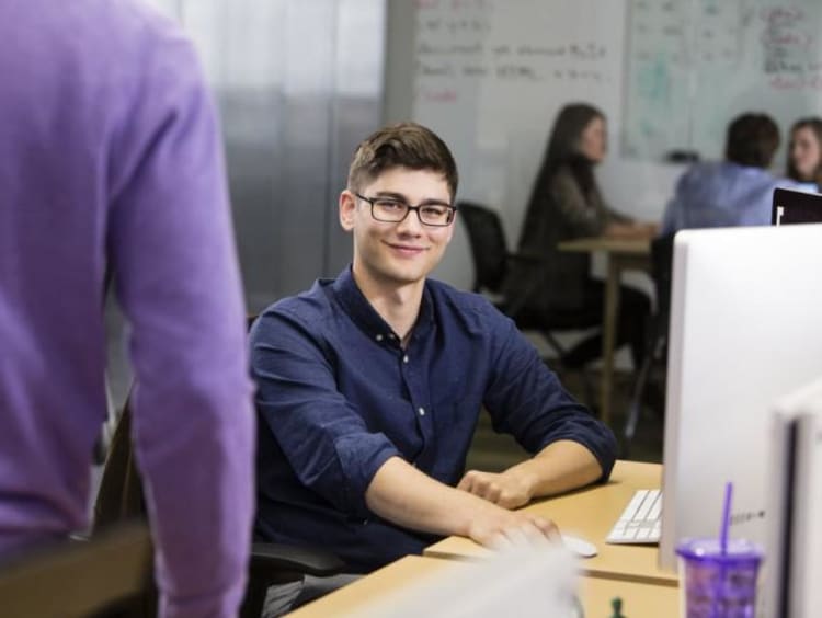 student sitting at a computer smiling