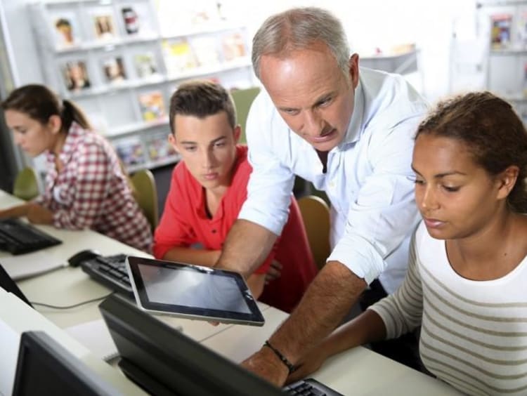 teacher helping student with a computer