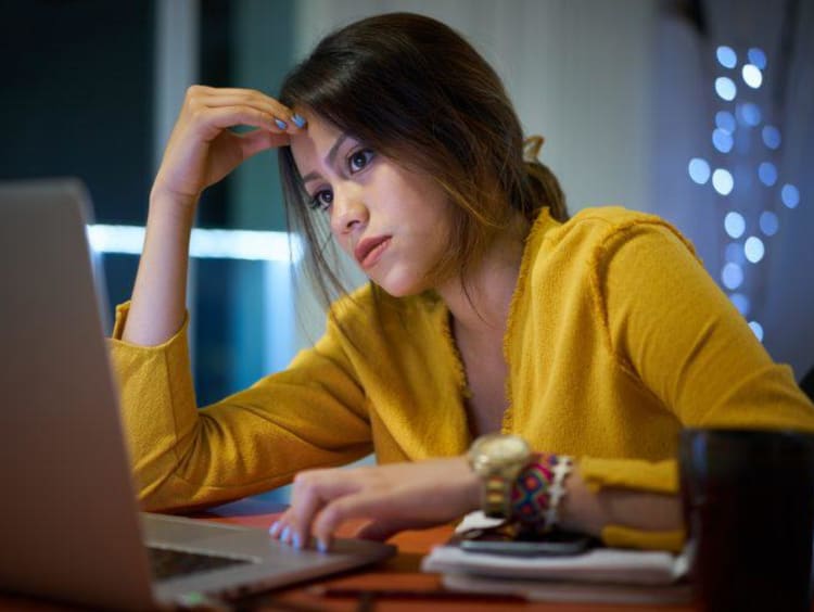 Exhausted female student looks stressed while using laptop